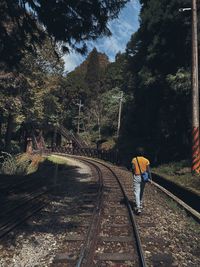 Rear view of man standing on railroad track