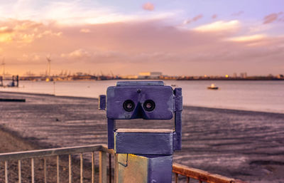 Close-up of binoculars at beach during sunset