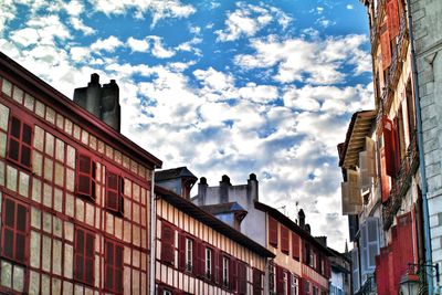 Low angle view of buildings against cloudy sky