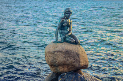 Sculpture on rock by sea