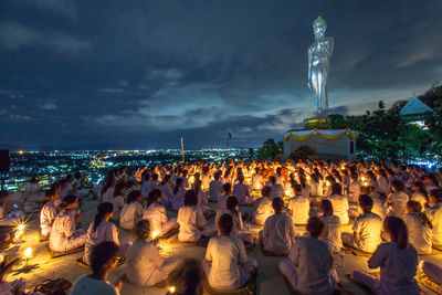 Group of people against illuminated sky at night