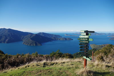 Sign board on grassy field against sea 