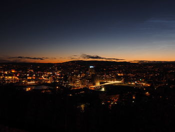 Illuminated cityscape by sea against sky at night