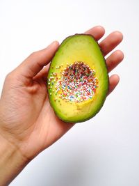 Close-up of hand holding fruit over white background