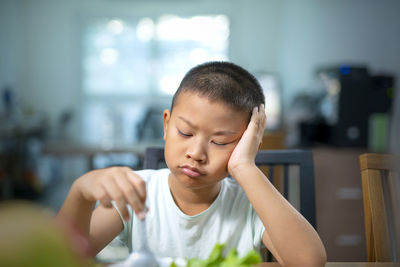 Close-up of sad boy eating food at home