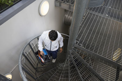 Young male technician carrying tool box on stairs