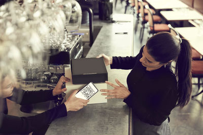 Owner and coworker with modem box at checkout counter in cafe