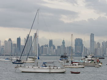 Sailboats in sea against buildings in city