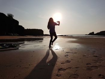 Silhouette man standing on beach against sky during sunset