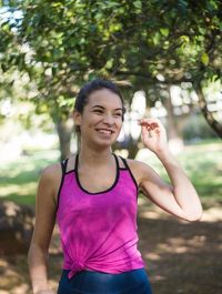 Portrait of smiling young woman standing against trees