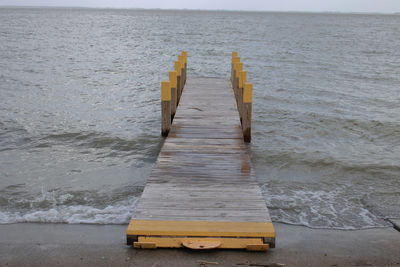 Wooden jetty in sea against sky