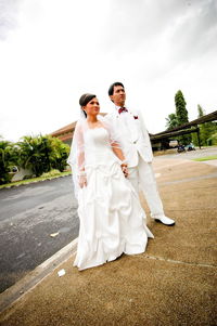 Bride and groom standing on footpath