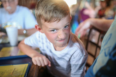 Portrait of angry boy sitting at restaurant