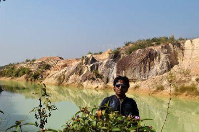 Portrait of man standing by lake against sky