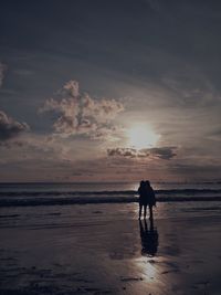 Silhouette of man with dog on beach