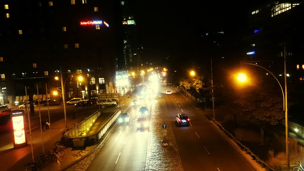 transportation, illuminated, night, car, city, mode of transport, land vehicle, building exterior, street, street light, traffic, architecture, built structure, road, city street, city life, on the move, high angle view, the way forward, wet