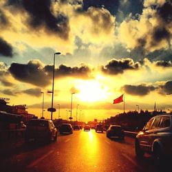 Traffic on road against cloudy sky at sunset