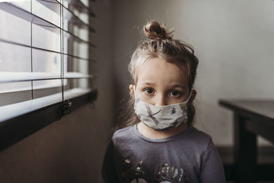 Close up portrait of preschool age girl with mask on looking at camera