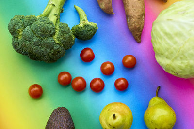High angle view of vegetables with fruits on colored background