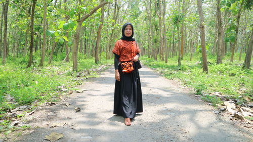 Full length portrait of woman standing in forest