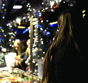 Rear view of woman with illuminated lights at night