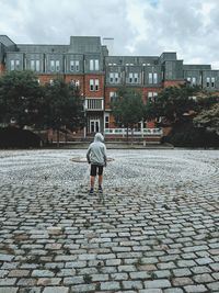 Rear view of woman walking on street against buildings in city