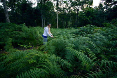 Young woman standing by trees in forest