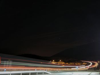 Light trails over street against sky at night