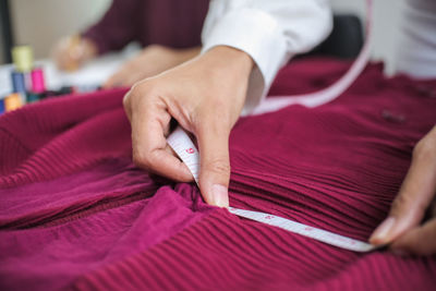 Midsection of man measuring cloth with tape measure