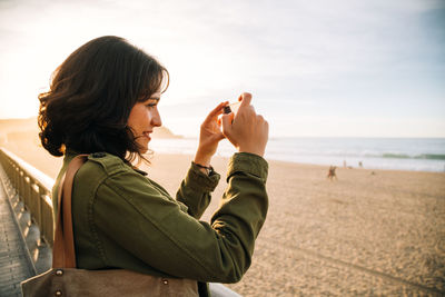 Side view of young woman on beach against sky