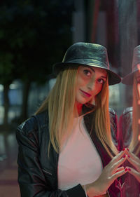 Young  woman with long hair and hat leaning on the glass of a shop window with a nostalgic look 