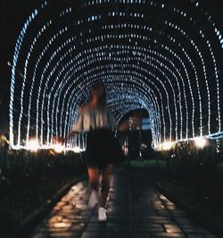 Rear view of man in illuminated tunnel