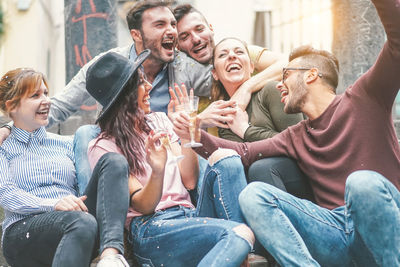 Cheerful male and female friends enjoying party during sunny day