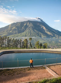 Back view of man standing on mountain against sky