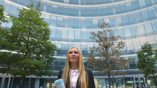 Businesswoman with blond hair standing outside office building