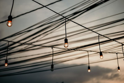 Low angle view of illuminated light bulbs hanging from ceiling