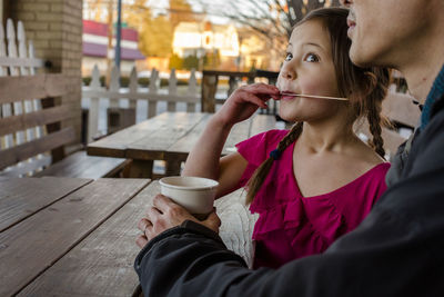 A happy girl enjoys a cup of cocoa with her father in an outdoor cafe