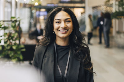 Portrait of happy young businesswoman standing at networking event in convention center