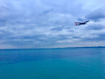 Airplane flying over sea against sky