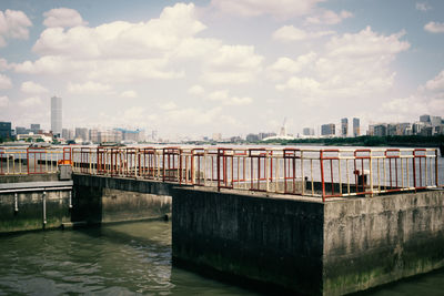 Bridge over river by buildings in city against sky