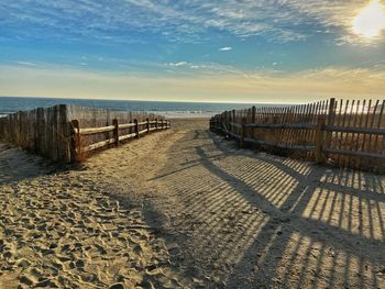 Wooden posts on beach against sky