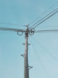 Low angle view of electricity pylon against clear sky