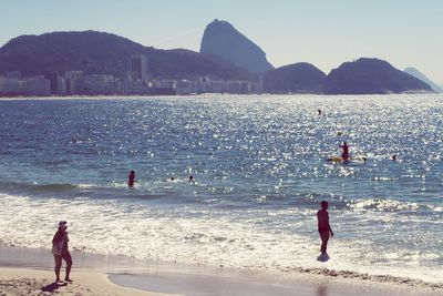 People standing on beach by sea against sky