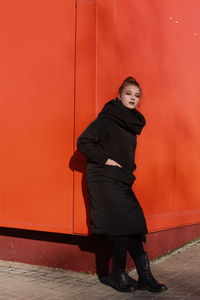 Portrait of woman standing against red wall