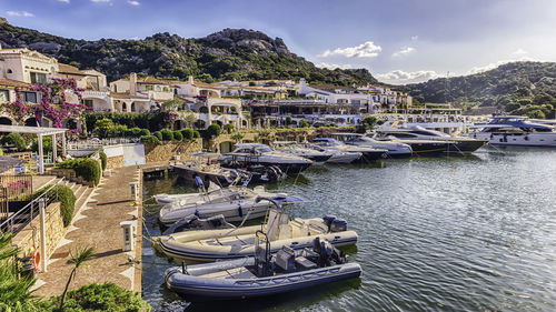 Boats moored in harbor by city against sky