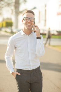 Cheerful businessman talking over mobile phone while standing on street