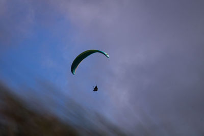 Low angle view of person paragliding against sky