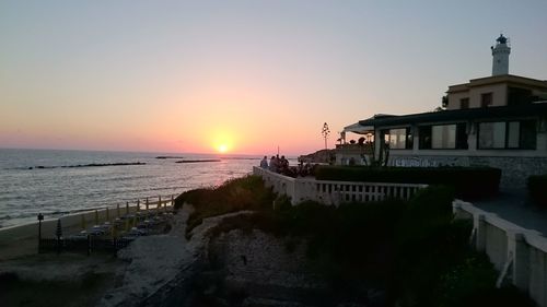 Scenic view of sea against buildings during sunset