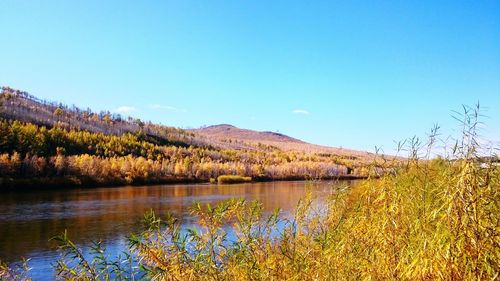 Scenic view of lake by mountains against clear sky