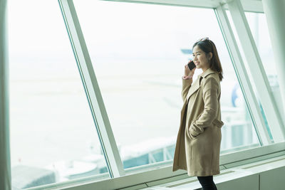 Side view of young woman looking through window